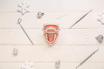 Jaw model with dental tools and Christmas balls on white wooden background