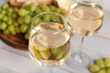 Glasses of exquisite wine on white wooden background