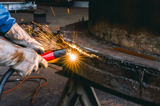 Welder use carbon air arc gouging for hot work cutting or gouging heavy metal steel structure in the fabrication factory.