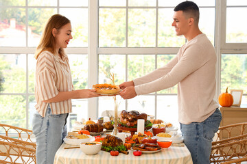 Young couple having dinner at festive table on Thanksgiving Day