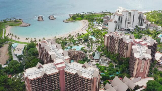 Cinematic aerial luxury beachfront hotel. Drone view family hotel with scenic blue beach lagoon. Top down on Ko Olina resorts on Oahu island Hawaii USA tourism. Palm trees exotic travel paradise 4K
