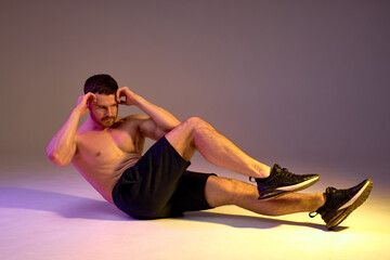 muscular man doing sit-up. isolated brown background, free time, spare time, lifestyle, strength...