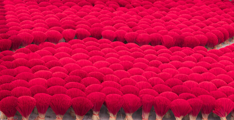 Vietnamese woman wearing conical hat is working for drying Incense sticks outdoor at yard