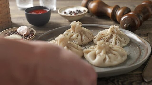 Hot khinkali on a ceramic plate. Traditional Georgian dumplings are served on a rustic wooden table.