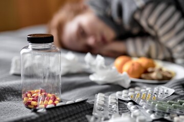 close up shot. focus on bottle of vitamins, pills medicine, unhealthy ginger woman sleeping in the blurred background