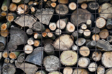 Dry firewood stacked in a pile, chopped wood for winter heating fuel of the fireplace. Natural wood...