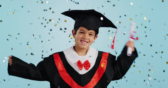 Graduate, child and celebration with confetti and happy dance in studio on blue background for education. Development, kid and success with excited expression, diploma or certificate for achievement