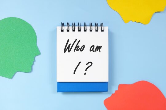 Who am I question in blue notebook. Self awareness and knowledge concept.