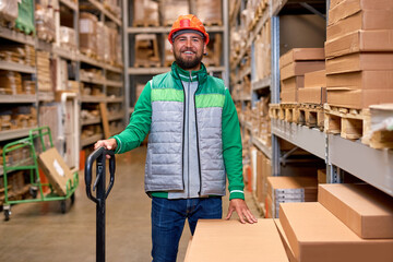 Warehouse worker holding a pallet truck going to upload package box to shelf in large warehouse....