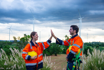Two Engineers working in wind turbine farm doing High five encouragement, Sustainable energy industry concept, Renewable energy solution for climate change