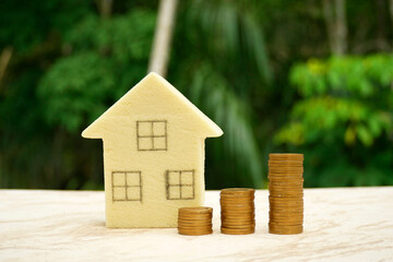 Miniature houses and piles of coins are used as concepts for saving money buying a house, New Year property, business, real estate, and Stable property prices concepts. 