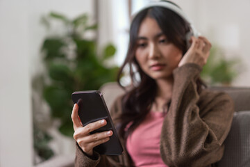 Women wearing headphones and watching movie with entertainment on smartphone in lifestyle at home