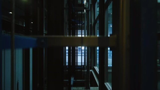 Modern glass elevator descending to the ground floor in a commercial building. The elevator going down.