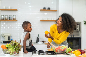 Portrait of enjoy happy love african american family mother and african little boy son child having fun help cooking food healthy eat together with fresh vegetable salad and ingredient in kitchen