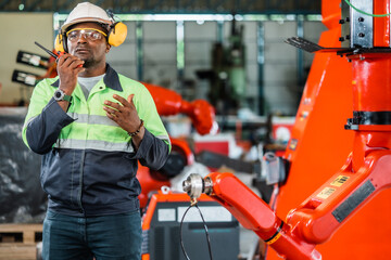 African American factory worker working with adept robotic arm in a workshop . Industry robot programming software for automated manufacturing technology .