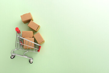 A shopping cart filled with delivery boxes on a green background