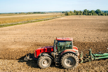 Obraz premium Tractor in the field. Agricultural machinery. Agricultural farm tractor during tillage of soil and field after harvest.