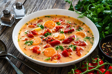 Tomato soup with cream on wooden table

