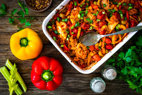 Jambalaya one pot dish - fried chicken breasts with white rice, tomatoes, bell pepper and celery on wooden table
