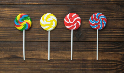 Four lollipops on a stick on a wooden background. The concept of sweets.