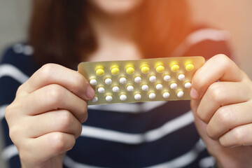 Woman hands opening birth control pills in hand. eating Contraceptive pill. Contraception reduces...
