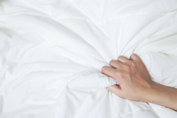 hand of female sex intimacy pulling white bedsheet in ecstasy on the bed, orgasm. Leave copy space...