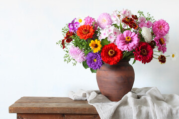 lush bouquet of garden autumn flowers in a clay jug.