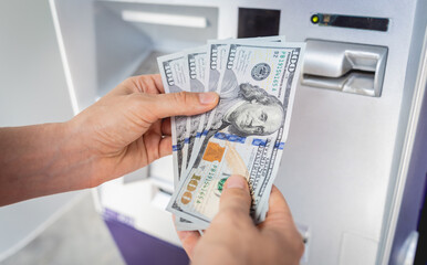 Young woman holding money in her hands after withdrawing the cash at the ATM