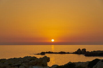 The stone coast of the Mediterranean Sea at sunset.