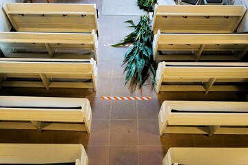 Innenausstattung von Kirche mit zwei Reihen weißer Holzbänke und langer grüner Maispflanze auf Boden an Erntedank - obrazy, fototapety, plakaty