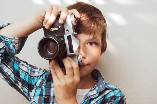 Small child taking photo with retro film camera. Old technology concept