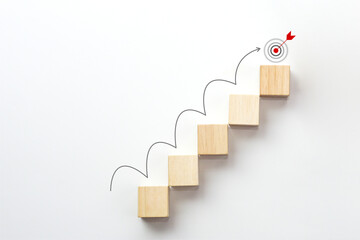 Wooden block stacking as step stair with arrow rising on white background and target icon on the...