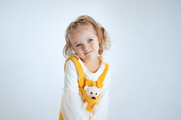 little girl in a yellow dress on a white background makes emotions