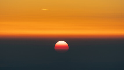 Sun rising through fog and smog early in the morning with orange sky, useable as background or banner