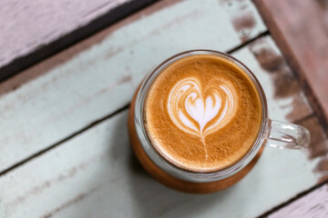Cup of coffee with latte art on vintage wooden table background.