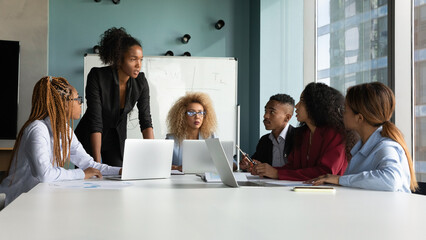 Confident African American businesswoman executive leading corporate meeting with colleagues, business partners negotiating in modern office boardroom, discussing financial project strategy