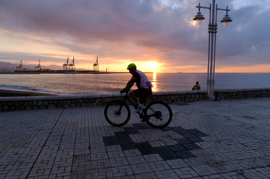 personas en el paseo mar&iacute;timo montando en bicicleta al amanecer junto a la playa