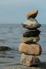 Balancing stones on top of each other in front of the sea