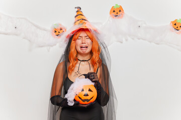 crying young asian woman in halloween costume looking at camera isolated over white background