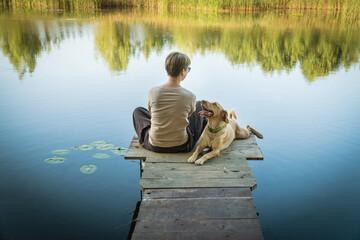 Female with a labrador dog on a wooden fishing bridge enjoying peaceful warm water view.