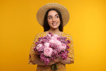 Beautiful woman with bouquet of spring flowers on yellow background