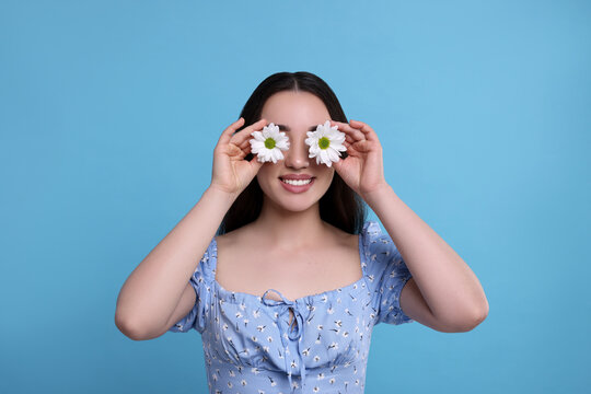 Woman Covering Her Eyes With Spring Flowers On Light Blue Background