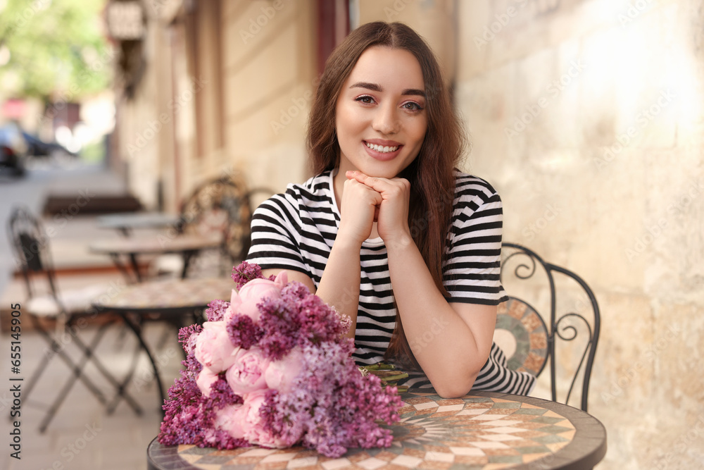 Poster Beautiful woman with bouquet of spring flowers in outdoor cafe