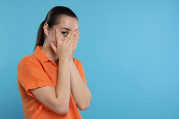 Embarrassed woman covering face on light blue background. Space for text - obrazy, fototapety, plakaty