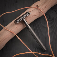 Classic men's shaving machine. Shaving accessories. Safety razor on a black background with wooden...