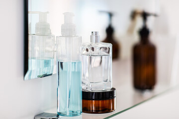 hygiene, beauty and daily routine concept - close up of lotion, perfume and moisturizer on mirror...