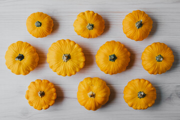 Beautiful freshly picked yellow mini pumpkins on white background, top view, flat lay style. Autumn seasonal pattern composition.