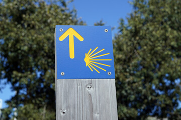 Blue sign with yellow emblems marking the way to Santiago de Compostela.