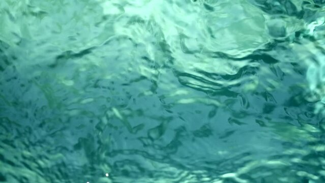 Blue water waves surface close up in swimming pool, background with copy space. 