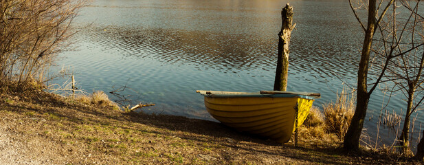 Scenic winter landscape. Old fisherman boat on the shore. Small yellow boat. Conceptual horizontal...